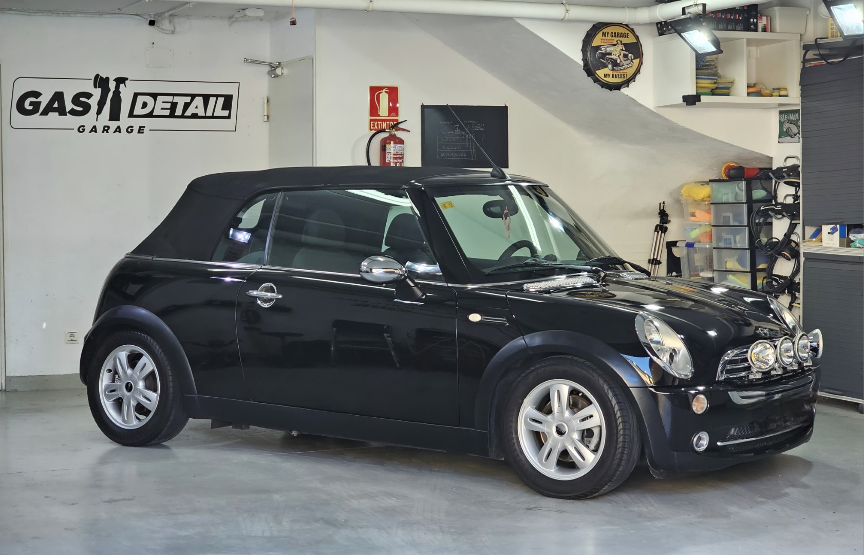 Coche negro convertible en taller de detalle.
