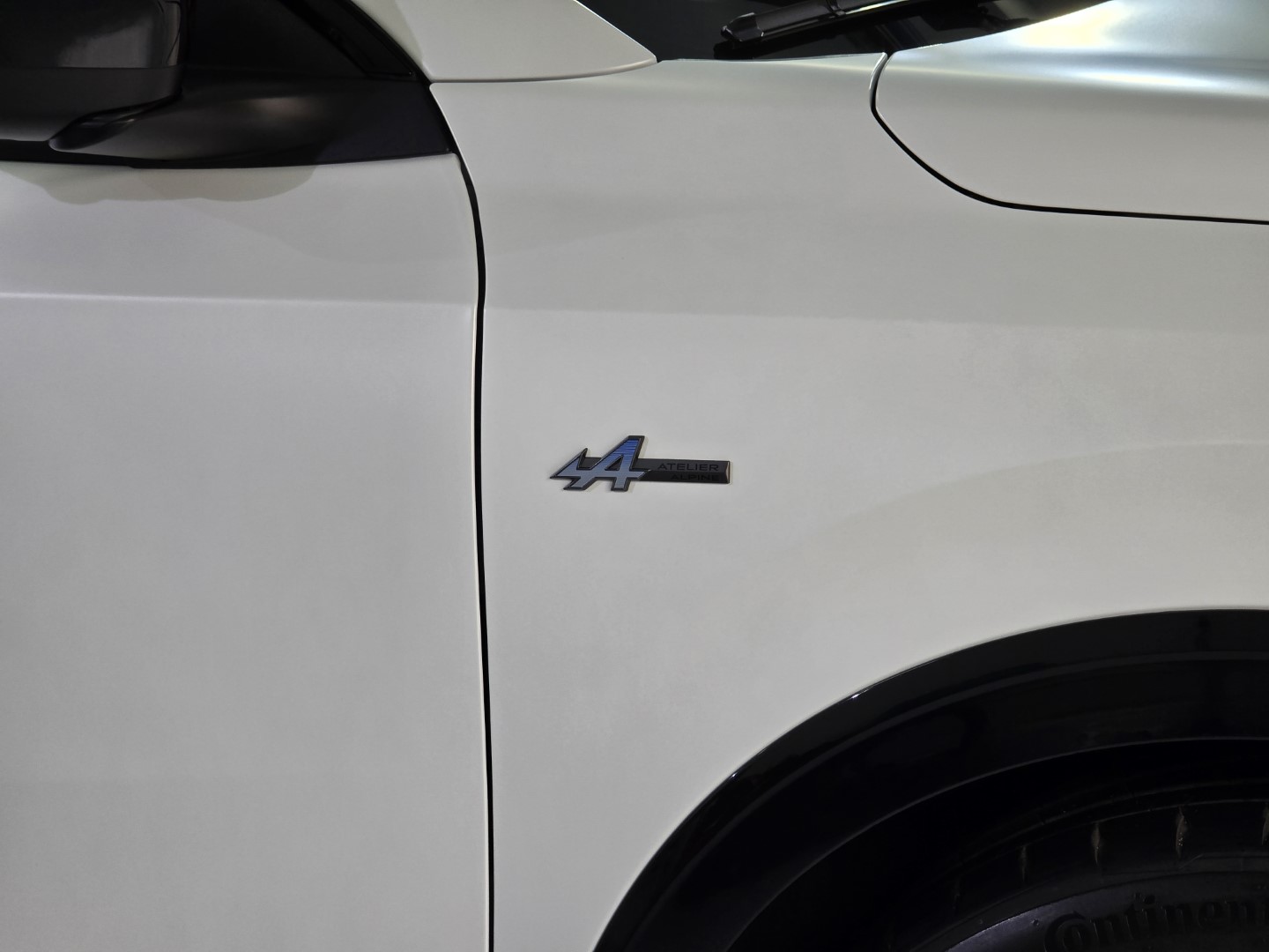 Detalle emblema lateral coche blanco.