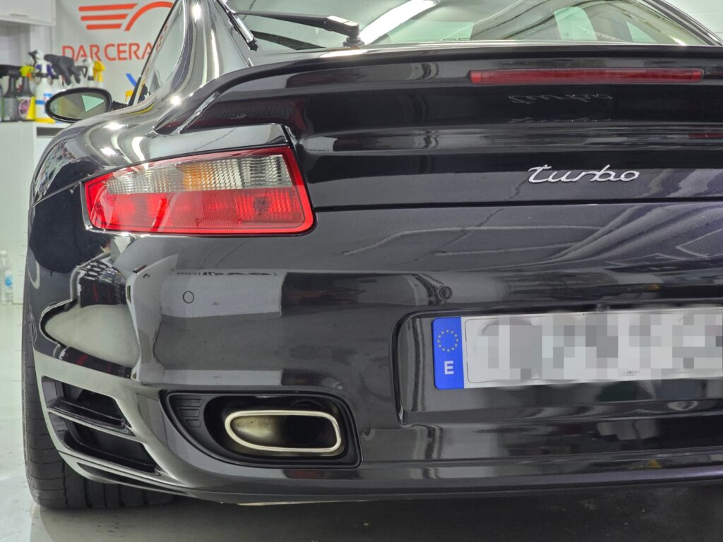 Parte trasera de coche deportivo negro, garaje fondo.