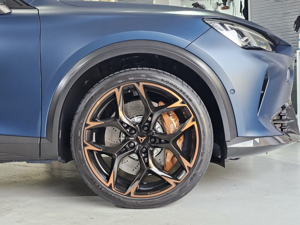 Rueda de coche deportivo azul con llantas negras y cobre