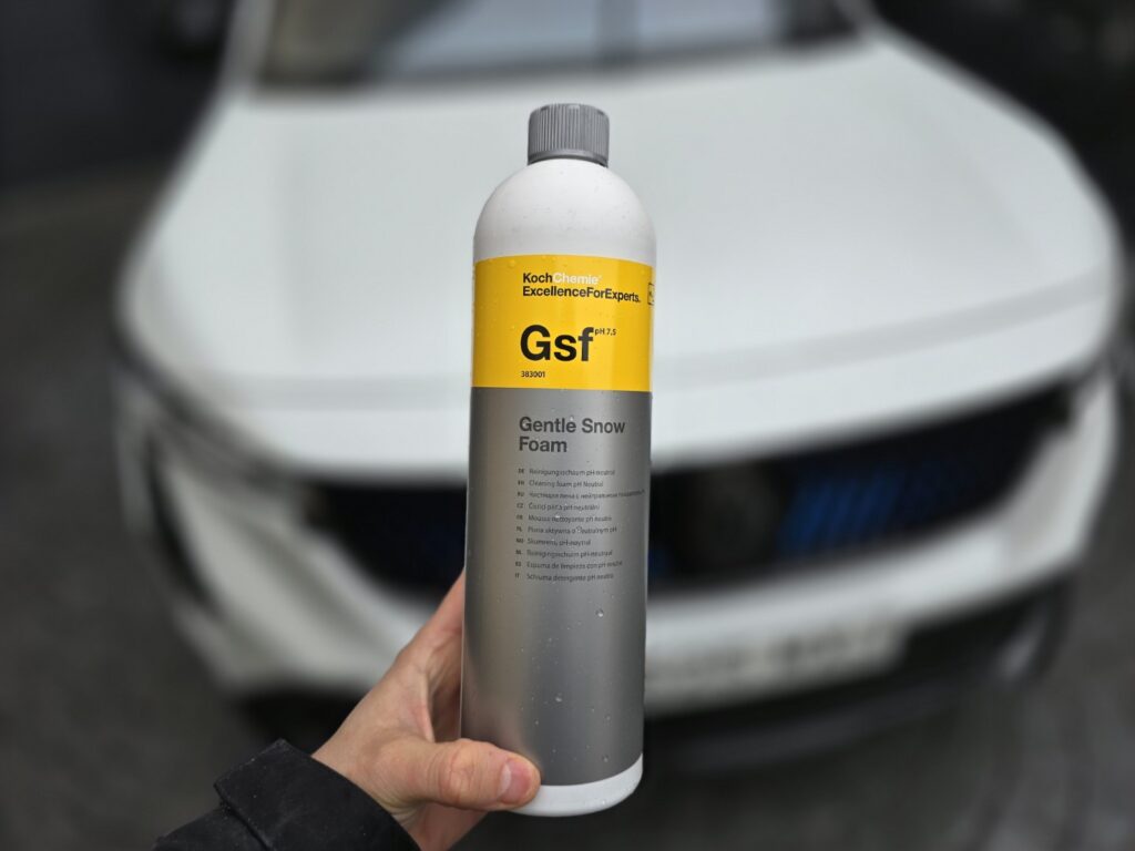 Botella de espuma suave frente a coche blanco